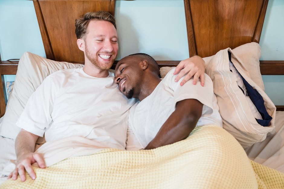 A joyful couple sharing a tender moment in bed, embracing and smiling.
