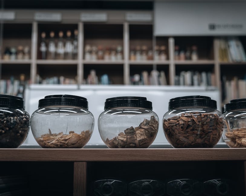 Glass jars with dried herbs and roots on a shelf in a traditional Korean pharmacy.