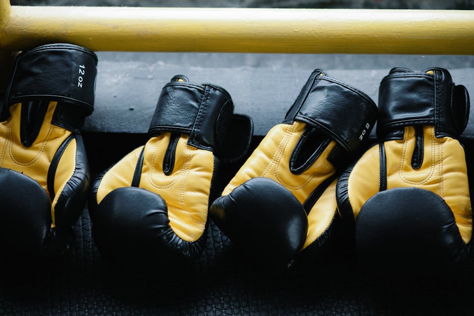 Pair of yellow and black boxing gloves resting on a gym floor.