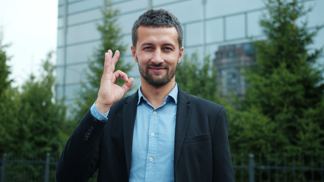 Man in suit gives okay sign with a smile.