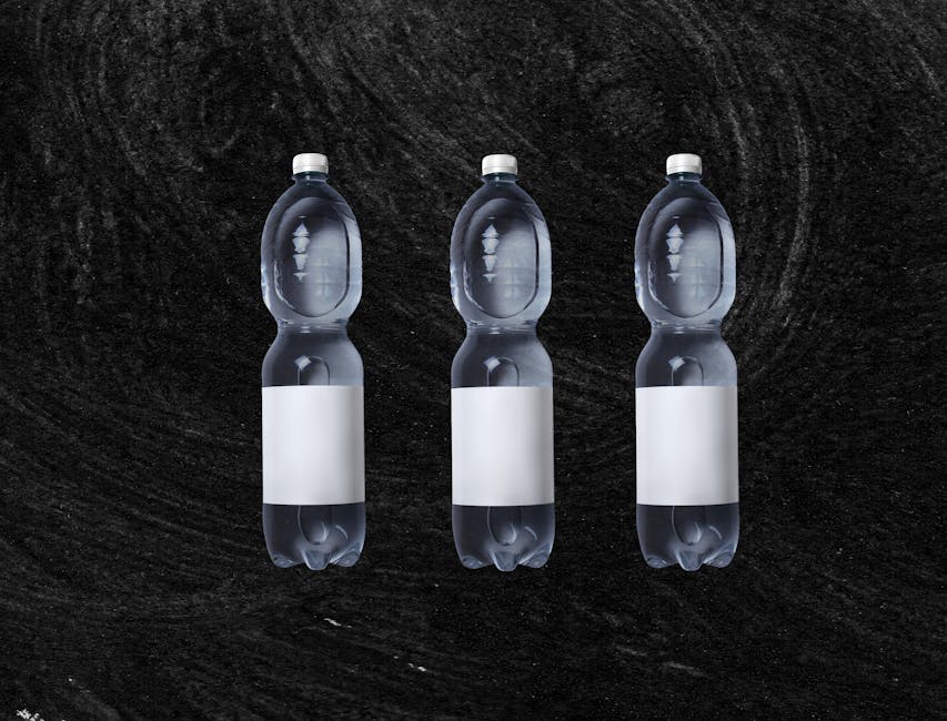 A set of three clear plastic water bottles on a textured black background, offering ample copy space.