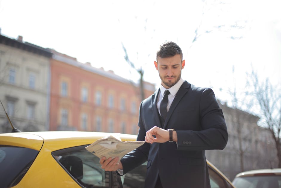 Corporate professional holding newspaper checks watch near a yellow car outdoors.