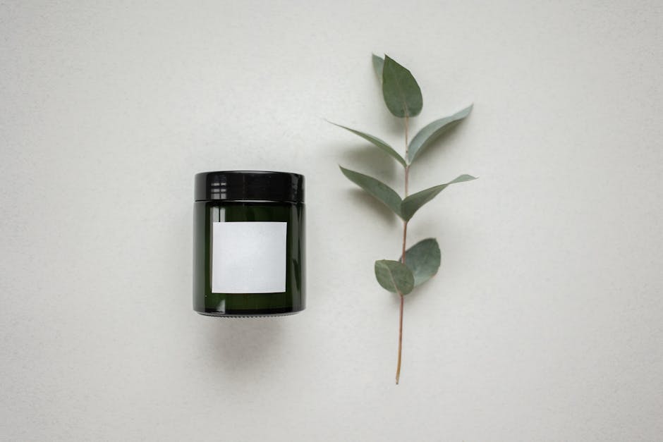 Elegant product mockup featuring a dark glass jar and eucalyptus on a white background.