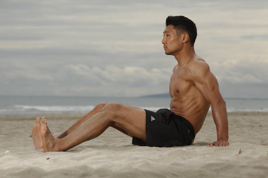 Fit young man sitting on a beach, enjoying a serene moment at the seaside.