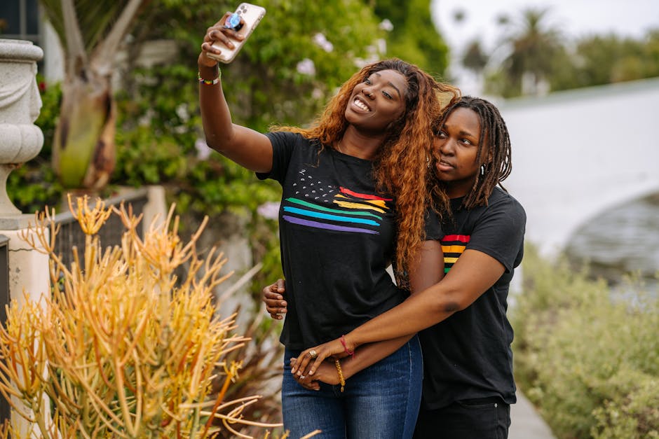 A loving couple capturing a selfie, enjoying the moment in LGBT pride shirts with a scenic background.