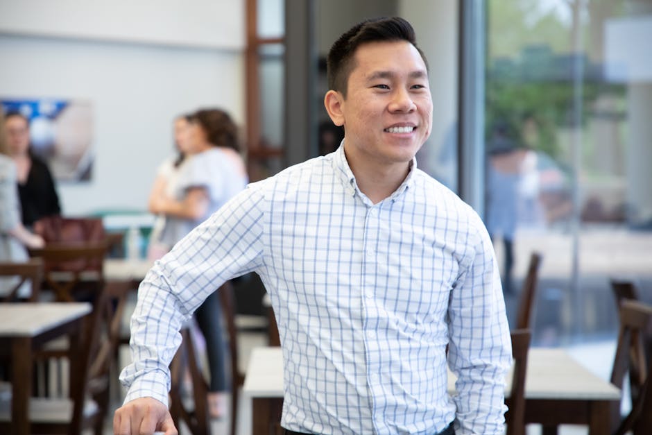 A happy Asian man in a casual office environment, exuding confidence and positivity.