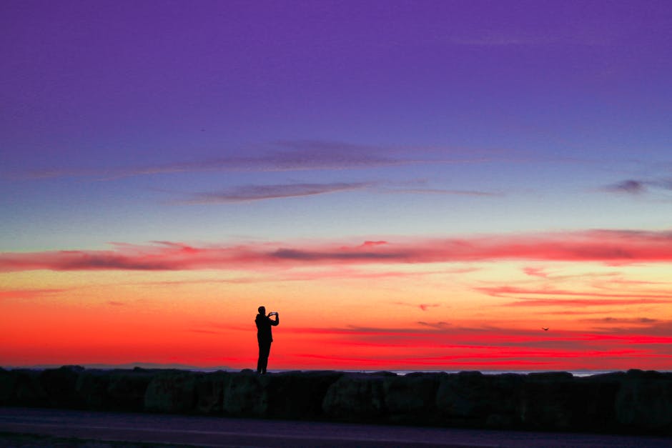 A striking silhouette of a photographer capturing a stunning sunset sky in İstanbul, Turkey.