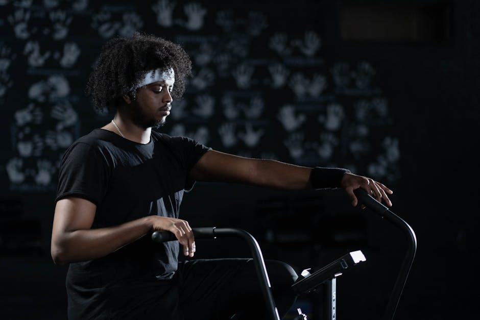 A man in activewear uses a stationary bike indoors, emphasizing fitness and wellness.