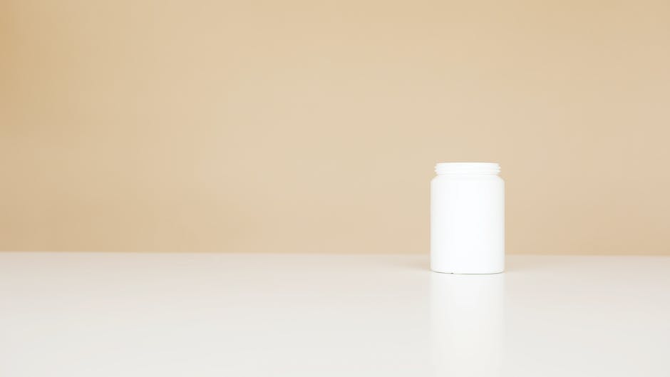 White plastic pills bottle left open on white table against light brown background