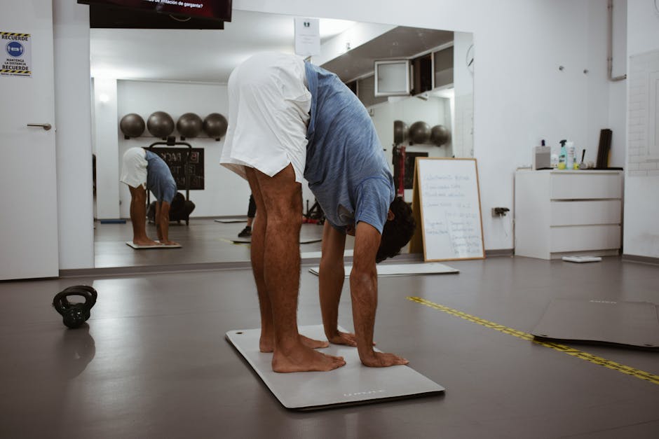 A man stretching on a gym mat with reflections in the mirror, promoting fitness health.