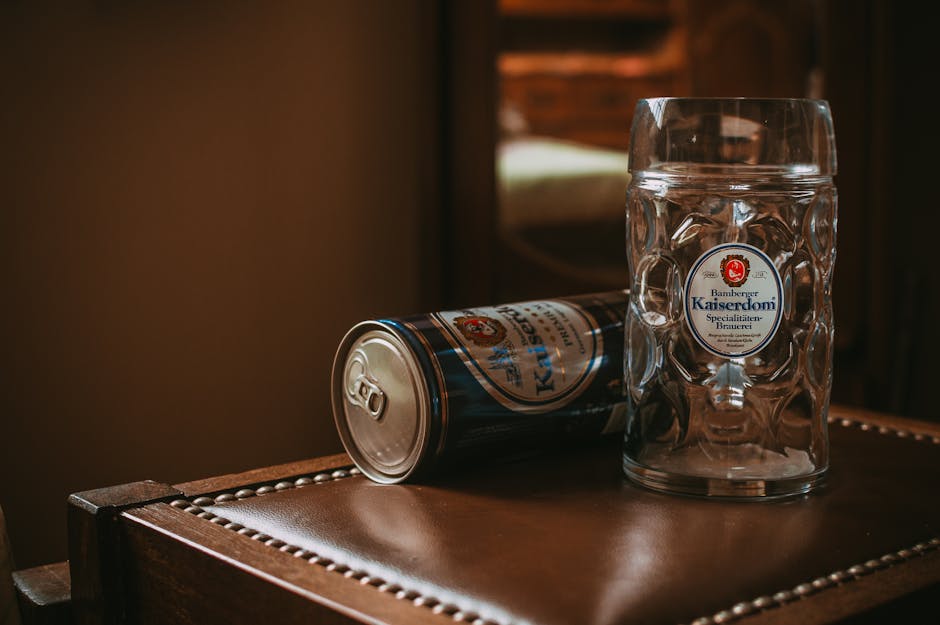 A large glass beer mug and a beer can on a wooden surface, cozy interior.