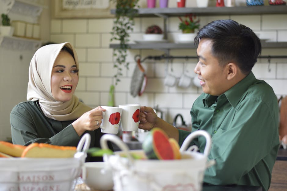 Smiling couple enjoying a warm drink while toasting in a cozy and stylish kitchen.