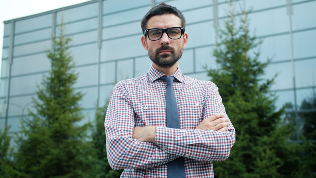 Man in glasses with arms crossed outside building