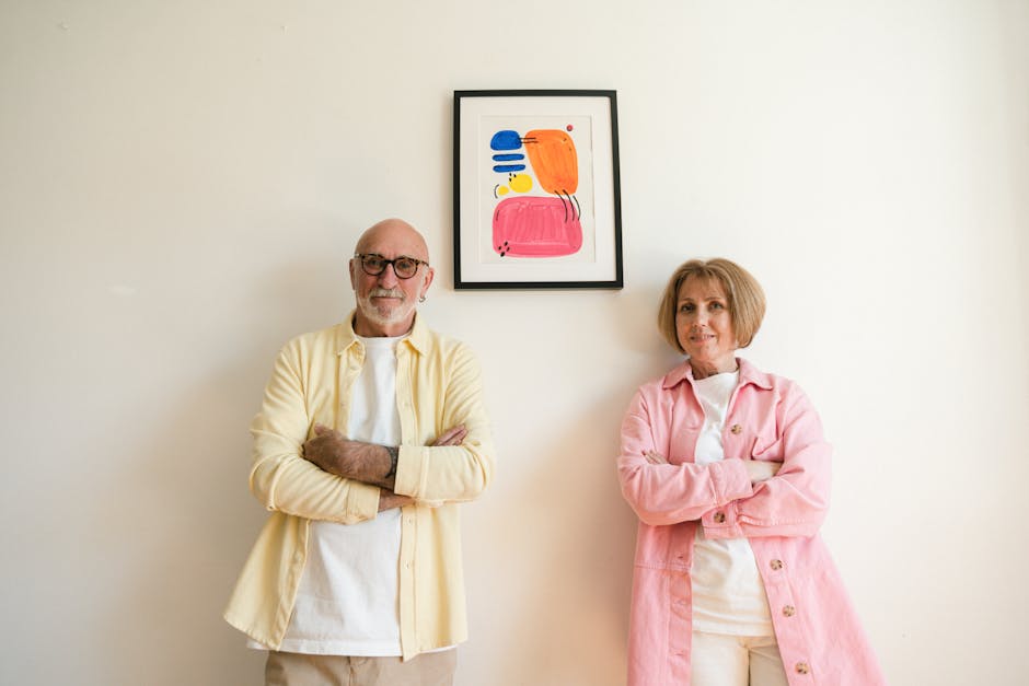 Chic senior adults with arms crossed, posing stylishly inside.